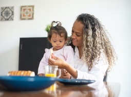 woman giving lunch to young child with Down's syndrome