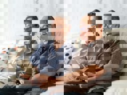 happy couple sitting on sofa looking at tablet