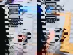 Woman using computer at a table next to a column of post it notes