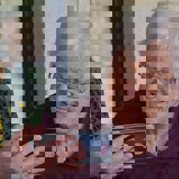 care worker wearing mask shows older woman a smartphone