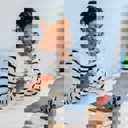 Smiling woman looking at computer with a cup of tea