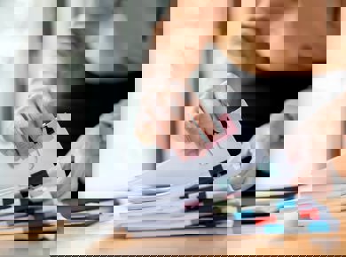 Person flicking through a pile of papers